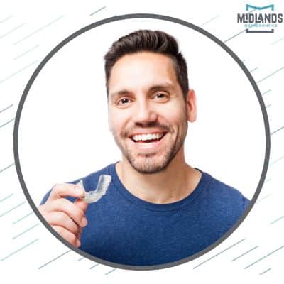 Man smiling and holding a clear aligner